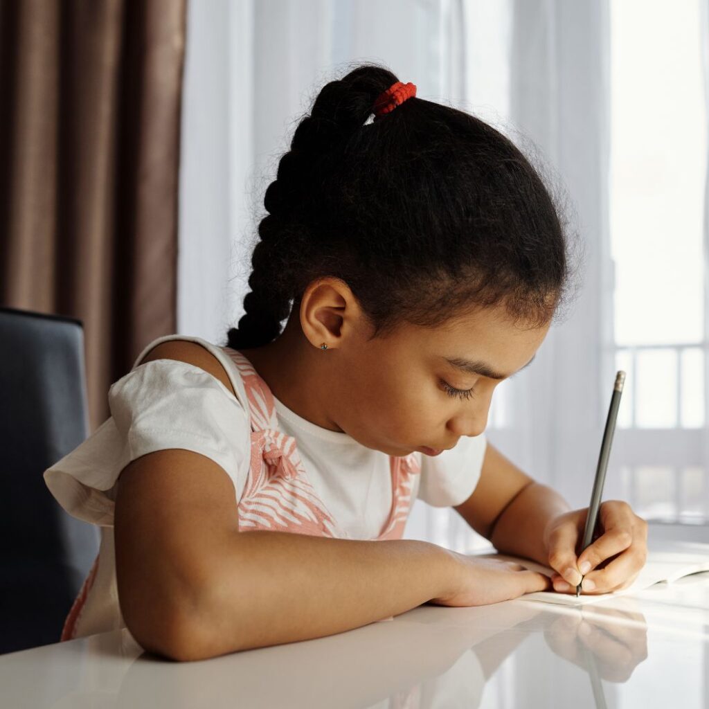 girl sat at a table writing